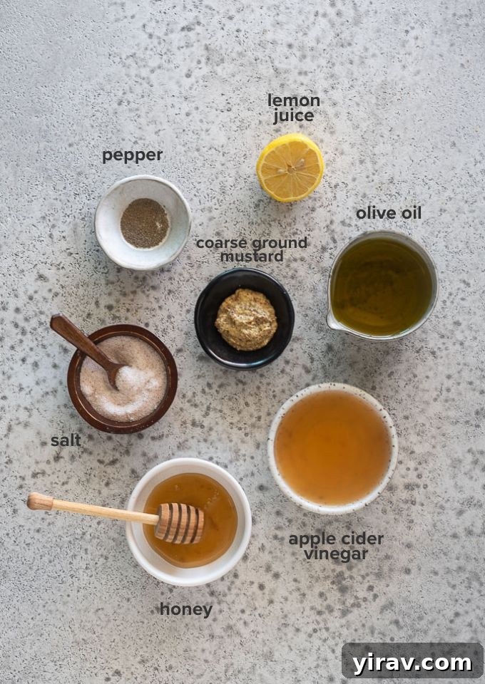 A selection of fresh ingredients laid out for making honey mustard dressing, including olive oil, honey, mustard, vinegar, and lemon.