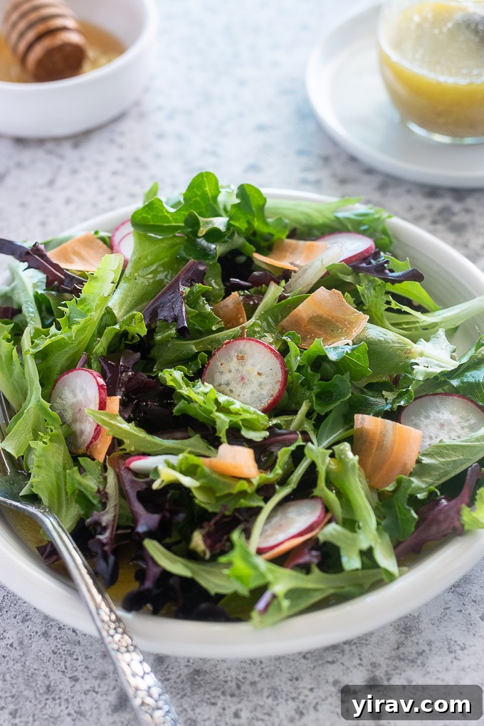 A bowl of fresh salad beautifully drizzled with homemade honey mustard dressing, ready to be enjoyed.