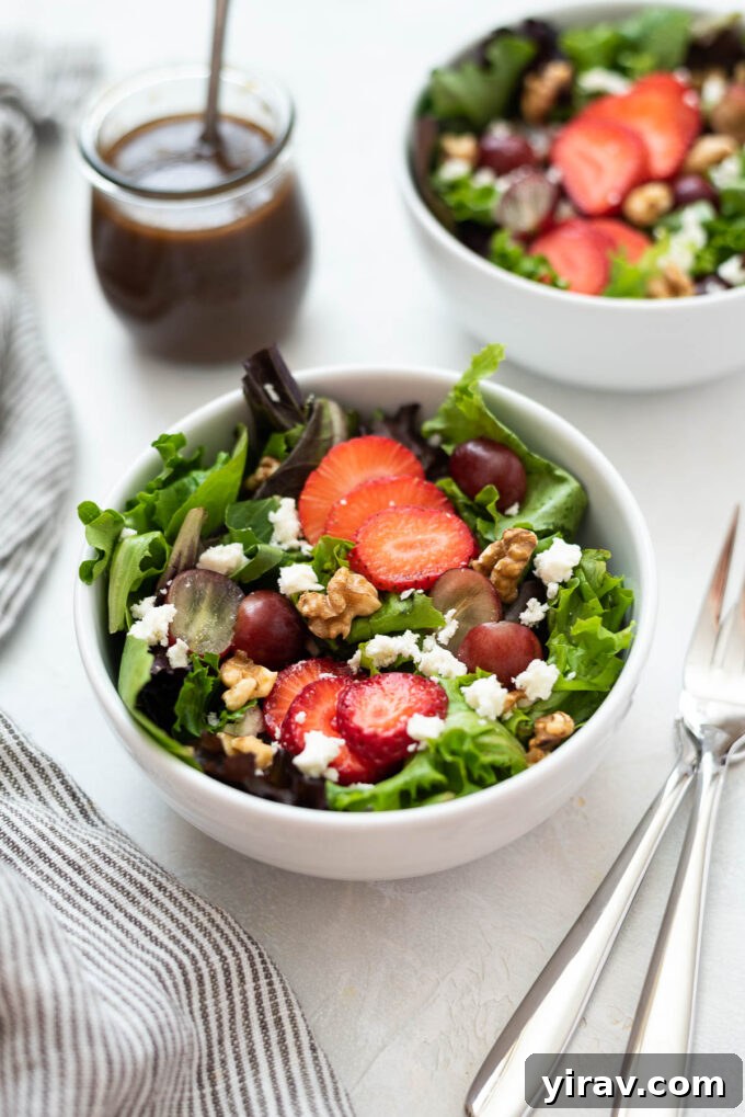 Refreshing Strawberry Feta Salad in a white bowl, packed with juicy strawberries, sweet grapes, feta cheese, and toasted walnuts.
