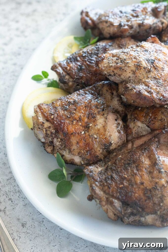 Grilled chicken thighs on a platter with lemon and oregano