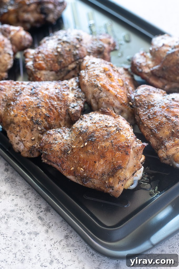 Grilled chicken thighs on a black tray fresh from the grill