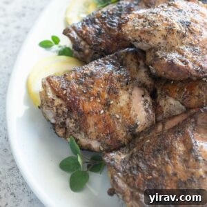 Grilled chicken thighs on a platter with lemon and oregano
