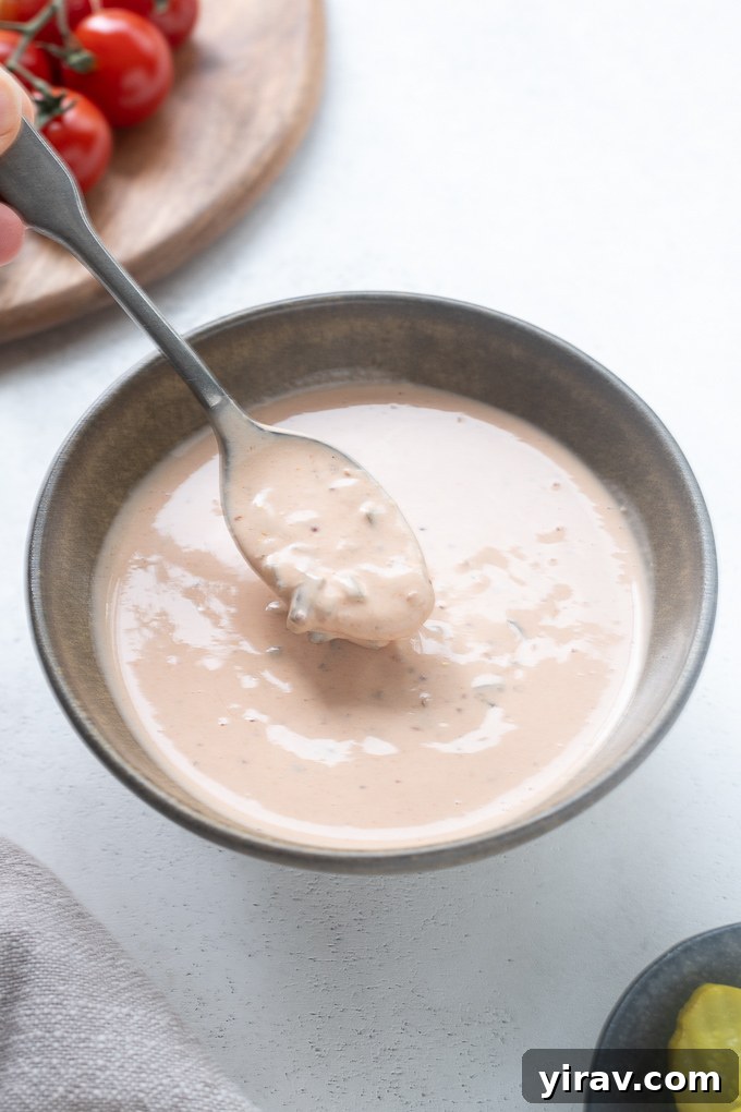 Spoonful of homemade burger sauce over a bowl