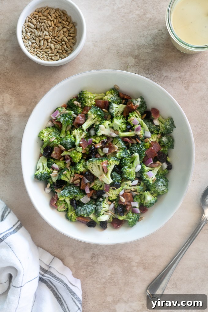 Broccoli salad recipe with bacon in a white bowl with a spoon alongside