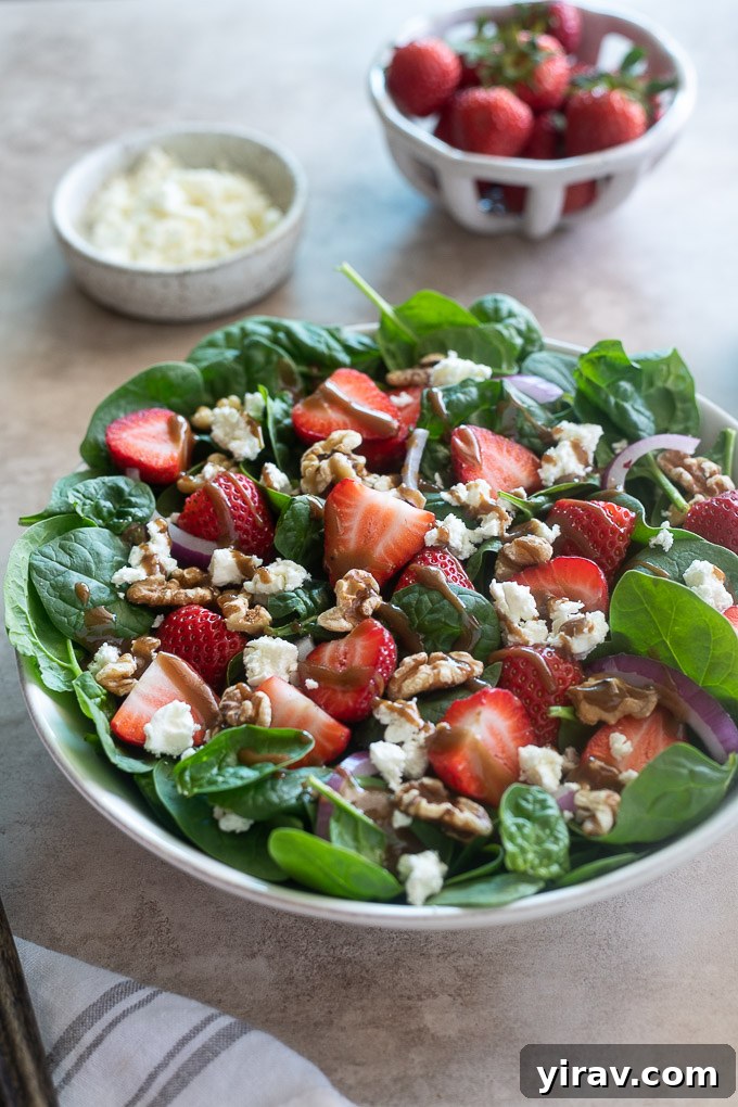 Close-up of spinach and strawberry salad in an elegant white serving bowl.