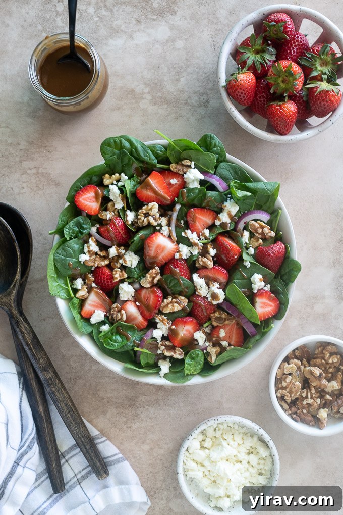 Strawberry spinach salad assembled in a bowl, awaiting its balsamic dressing.