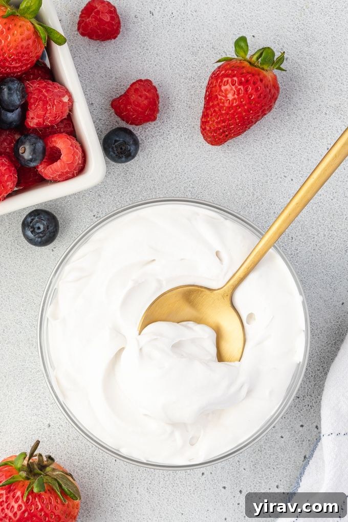 Freshly whipped coconut cream in a elegant bowl, beautifully garnished with a colorful assortment of fresh berries, ready to be served.