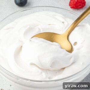 Spoonful of coconut cream whipped cream in a glass bowl.