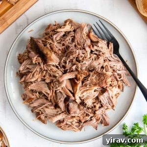Slow cooker pulled pork on a white plate, ready to serve