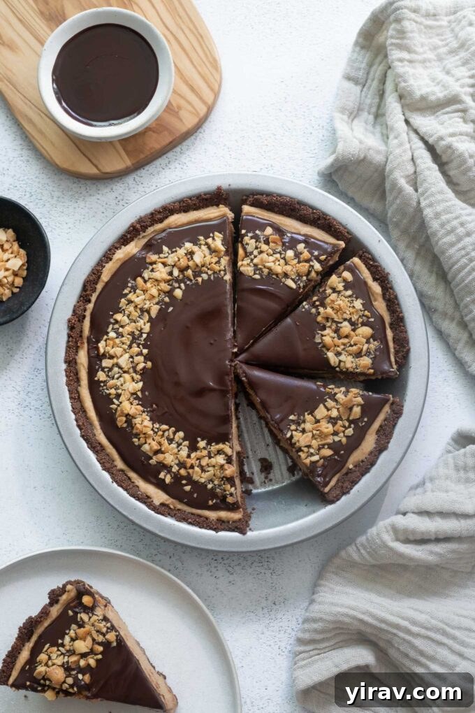 A slice of Chocolate Peanut Butter Pie, showcasing its layers of chocolate crust, creamy peanut butter filling, and chocolate ganache topping, with one piece missing from the whole pie.