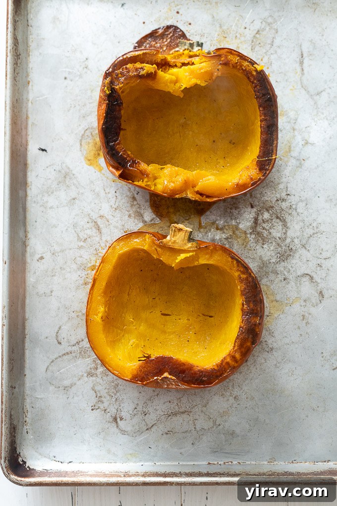 Two perfectly roasted pumpkin halves presented elegantly on a baking sheet, glistening with oil and seasoning.