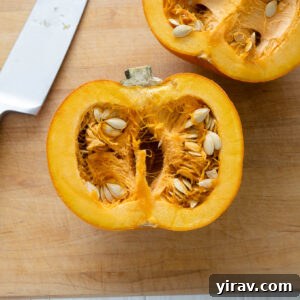 Pumpkin cut in half on a cutting board with knife