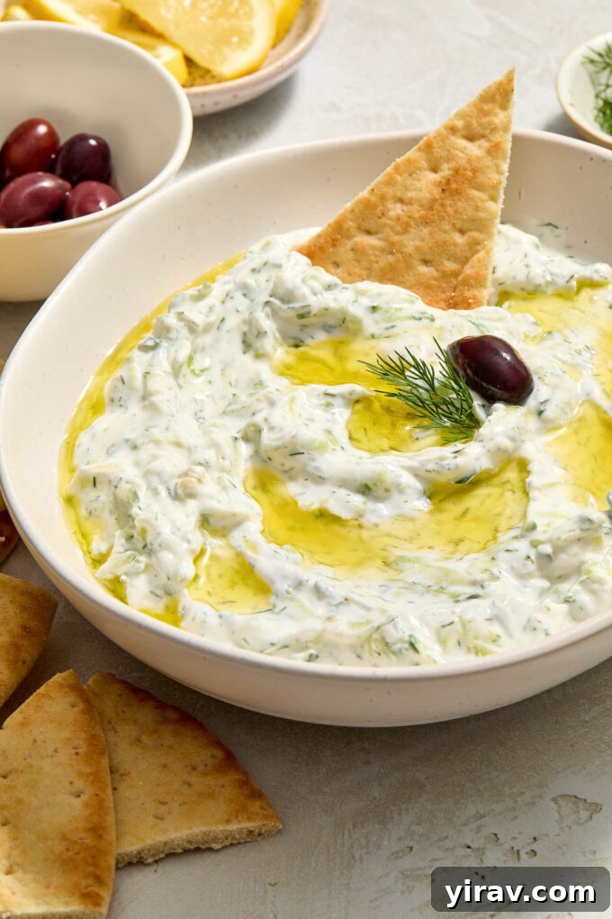 Greek tzatziki in a bowl with pita bread dipped in.