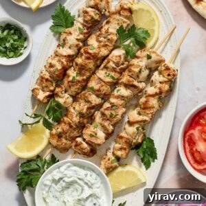 Greek chicken souvlaki on a platter with tzatziki sauce.