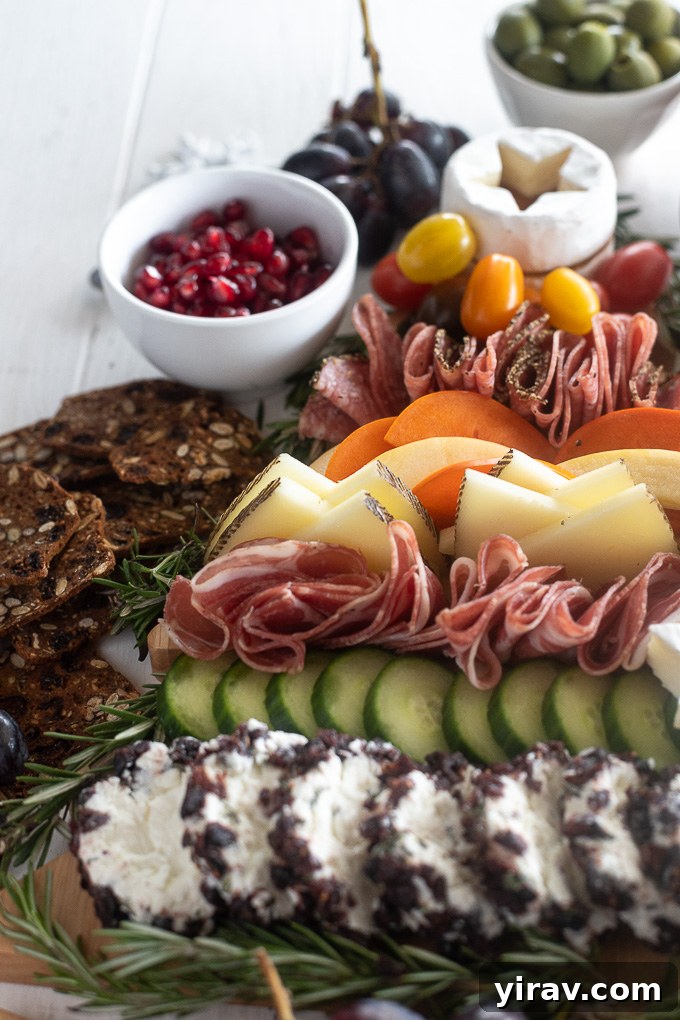 Edible Evergreen Board 3 Delicious Christmas charcuterie board featuring wedge-cut Manchego cheese, bright red pomegranate arils, cured meats, and fresh herbs, artfully arranged.