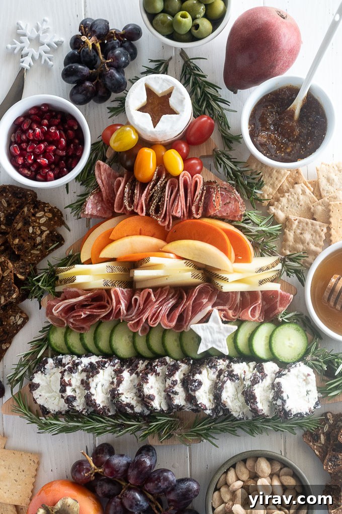 Edible Evergreen Board 8 Christmas charcuterie board surrounded by an assortment of crackers, fig jam, marcona almonds, and fresh red grapes, ready for holiday serving.