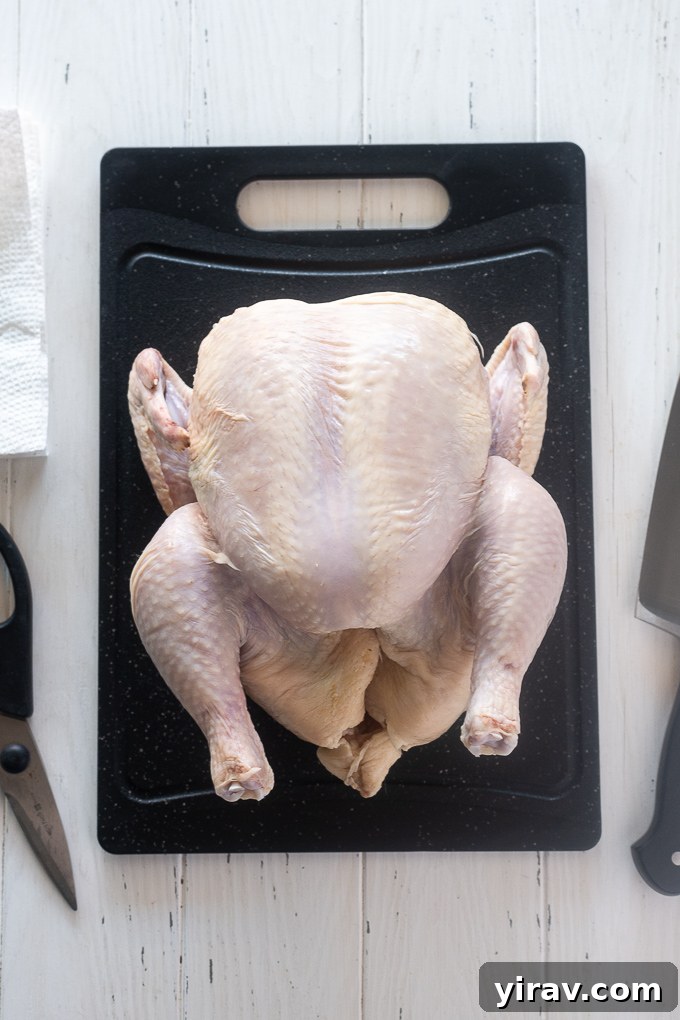 A collection of essential tools for cutting a chicken, including a chef's knife, kitchen shears, and a sturdy cutting board, laid out next to a whole chicken.