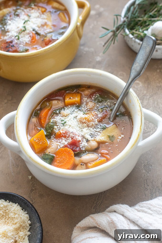 Hearty bowl of Autumn Vegetable Soup topped with grated Parmesan cheese and fresh herbs