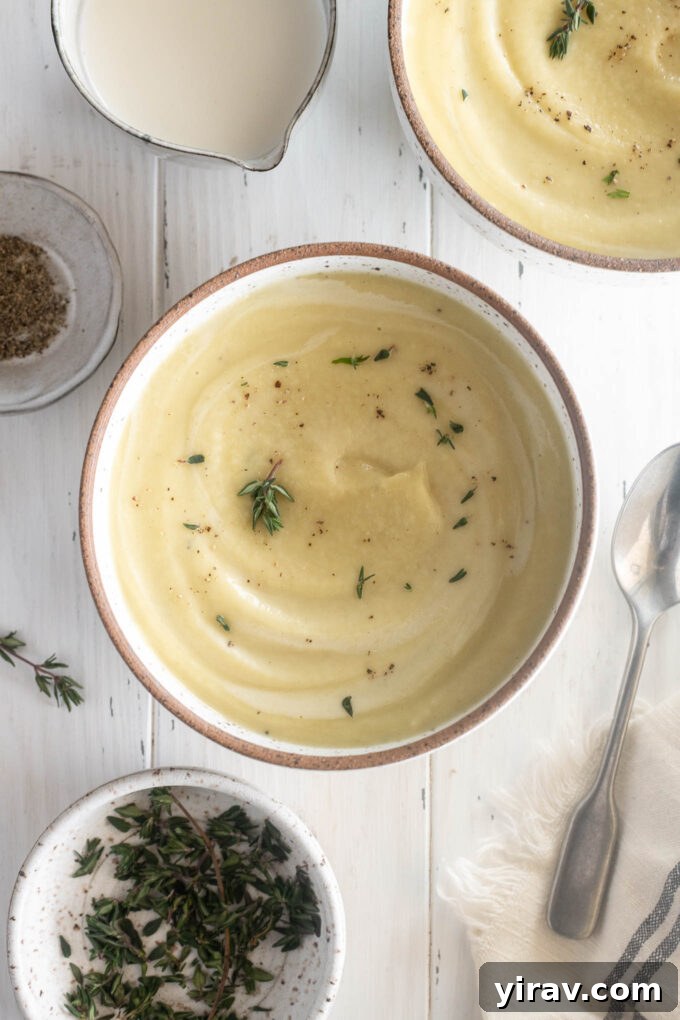 Creamy parsnip soup garnished with fresh thyme leaves in a white bowl