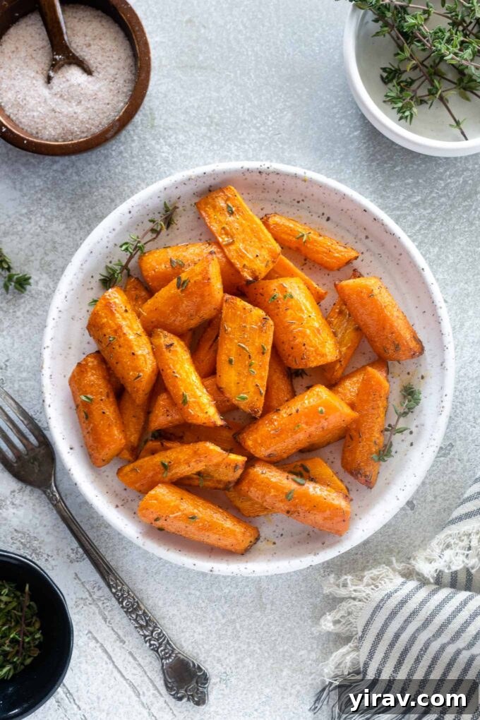 Effortless Air Fryer Roasted Carrots 2 Air fryer carrots on a plate with thyme leaves, ready to be served as a delightful side dish.