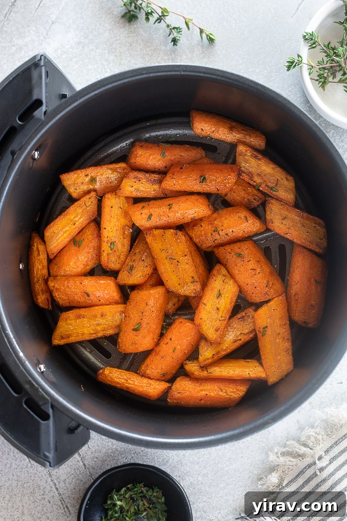 Effortless Air Fryer Roasted Carrots 3 Delicious roast carrots cooked in an air fryer, garnished with fresh thyme leaves.