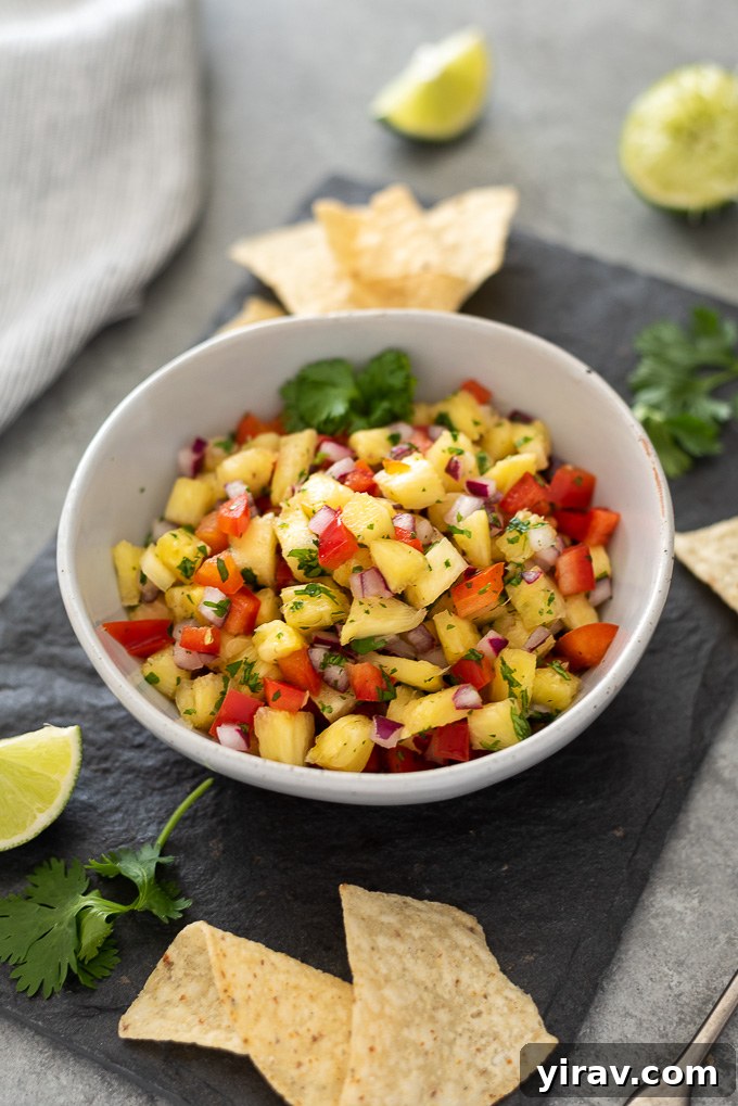 A rustic platter showcasing a bowl of pineapple salsa surrounded by an abundance of crispy tortilla chips, inviting guests to dig in.