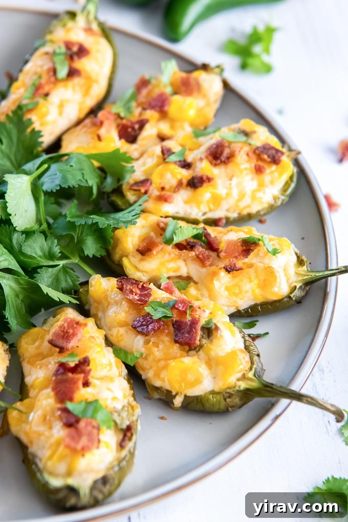 Stuffed jalapeno peppers on a serving plate with fresh cilantro garnish