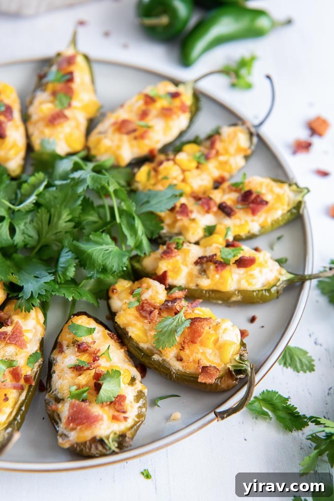 Stuffed jalapeño peppers on a serving plate, garnished with cilantro leaves