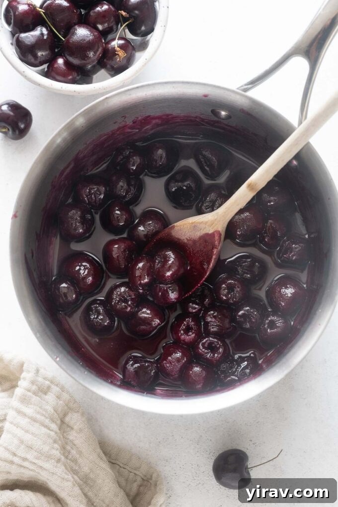 Ruby Red Cherry Bliss 6 Cherry sauce in a pot with a wooden spoon.
