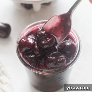 Spoonful of cherry compote over a jar.