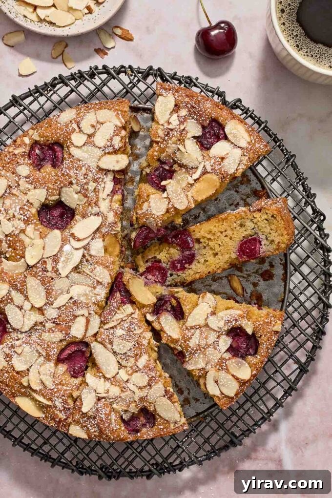 Cherry almond cake on a wire rack with slices cut.