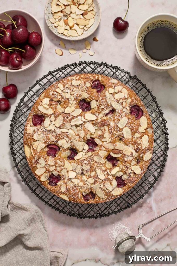 Almond and cherry cake unsliced on a wire rack.