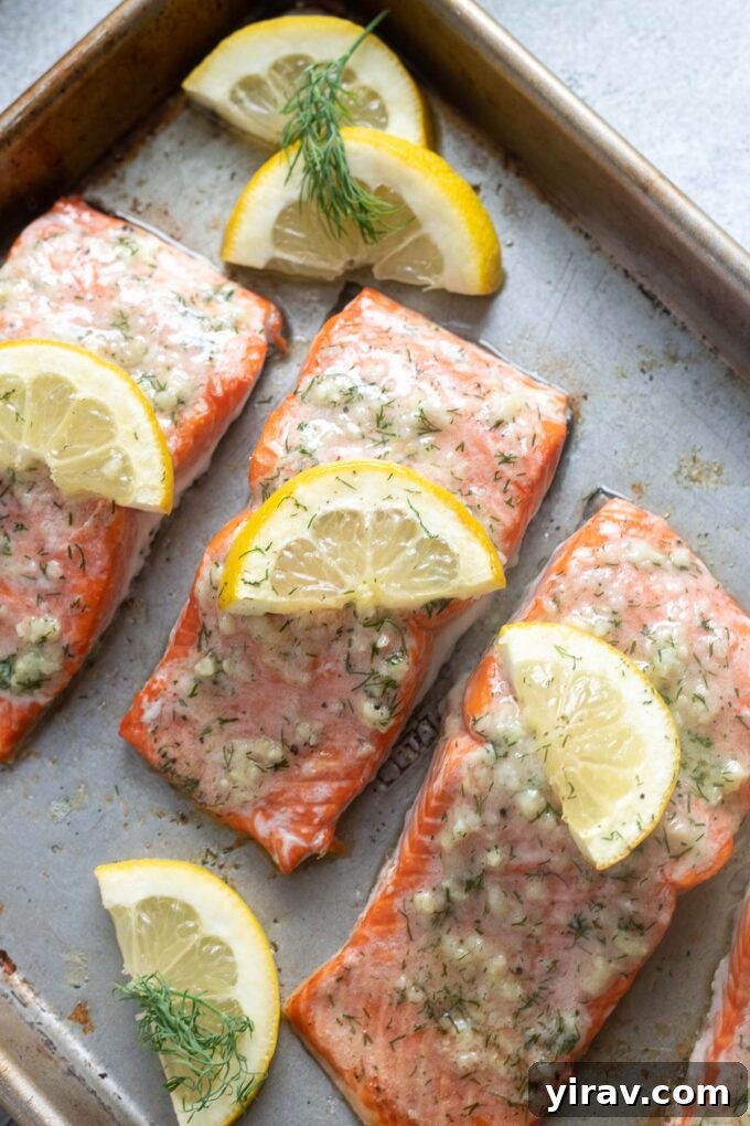 Irresistible Garlic Butter Salmon 3 Fresh lemon and garlic butter drizzled over salmon fillets on a baking sheet before cooking.