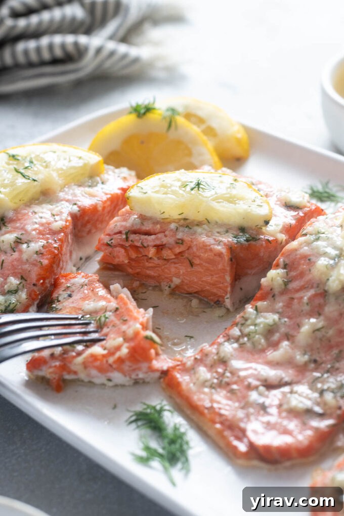 Irresistible Garlic Butter Salmon 7 A fork flaking into a piece of garlic butter baked salmon, showing its tender, moist texture.