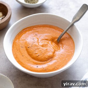 Roasted red pepper sauce in a bowl with a spoon digging in.