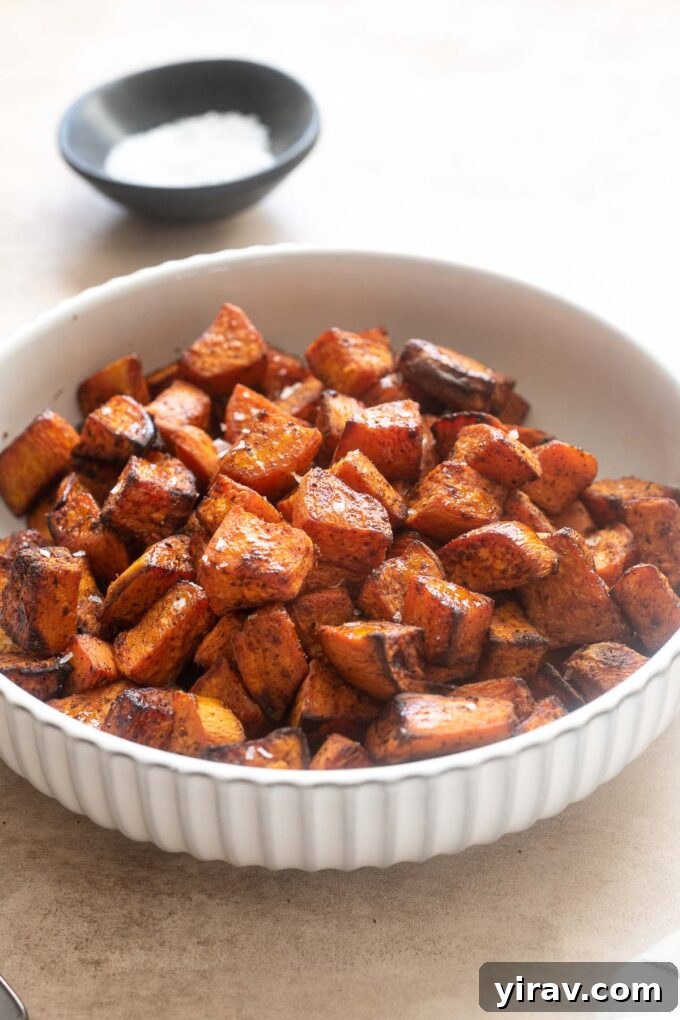 Air fryer sweet potato cubes seasoned with sea salt in a bowl, ready for cooking.