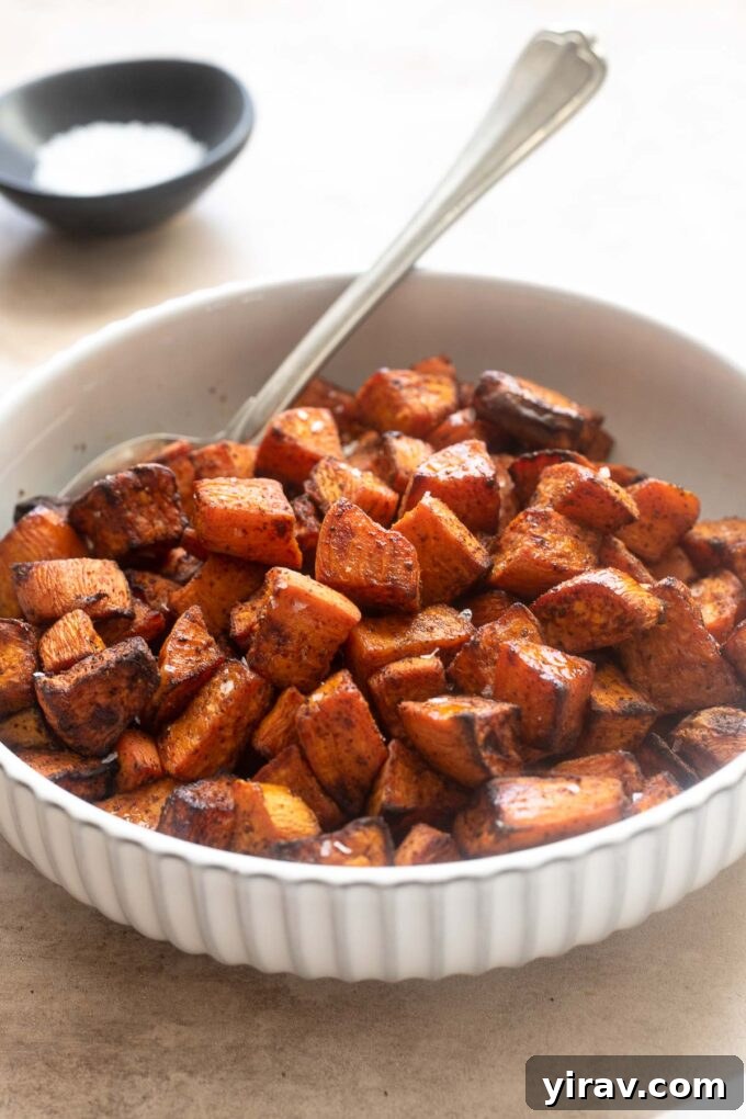A full white bowl of crispy air fryer roasted sweet potato cubes, garnished.