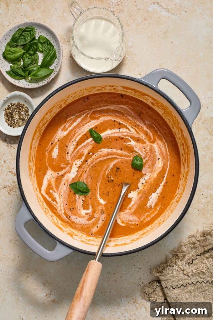 A large pot of creamy roasted tomato soup with a ladle, ready to be served.