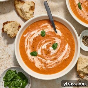 Creamy roasted tomato soup in a bowl with bread alongside, as featured in the recipe card.