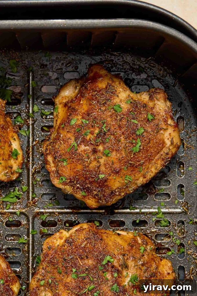 Raw bone-in, skin-on chicken thighs in an air fryer basket, ready for cooking.