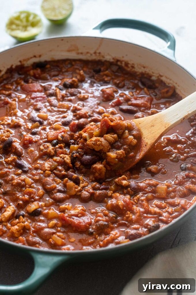 Chicken chili with ground chicken simmering in a large dutch oven.