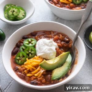 Bowl of ground chicken chili with a spoon digging in.
