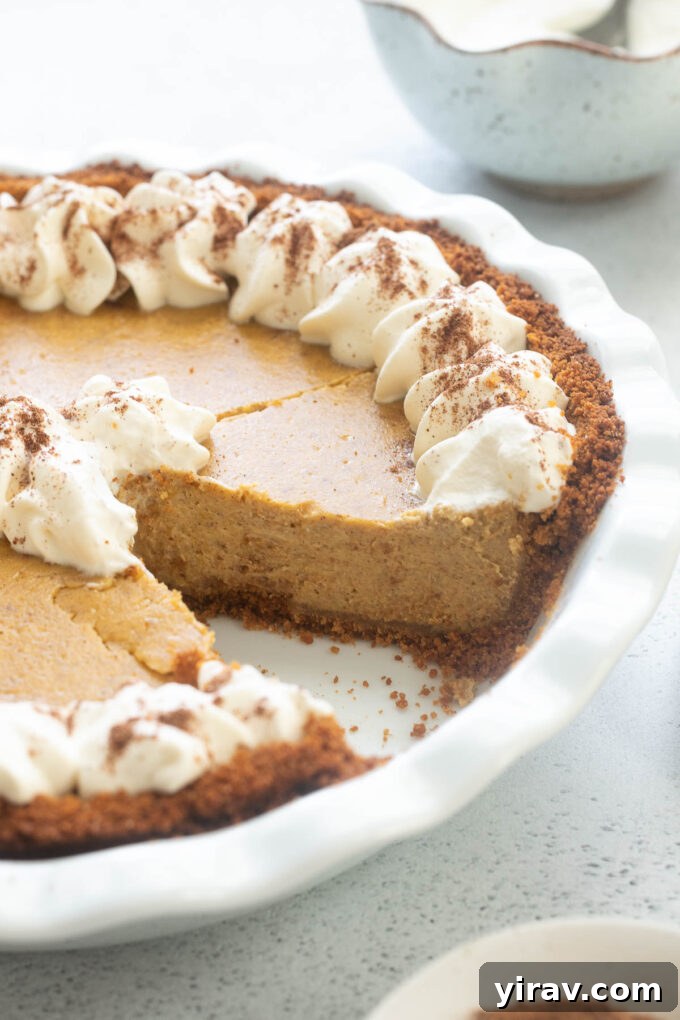 Autumn Spice Pumpkin Cheesecake Delight 6 Pumpkin pie cheesecake in pie dish with a slice missing.