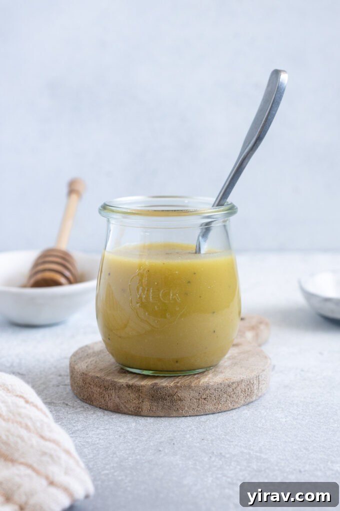 Sparkling Honey Champagne Dressing 3 Champagne vinegar dressing in a jar with a spoon inside.