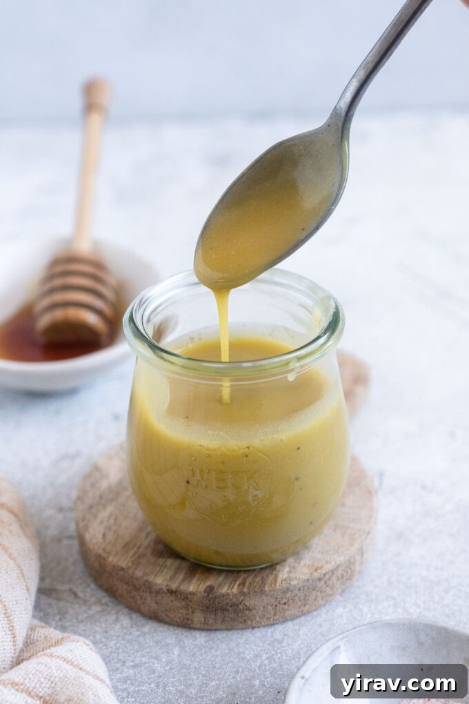 Sparkling Honey Champagne Dressing 6 Champagne vinaigrette pouring into a jar from a spoon.