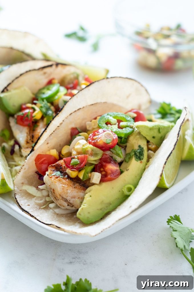 Grilled Fish Taco topped with vibrant cherry tomato salsa and creamy avocado slices, ready to be enjoyed.