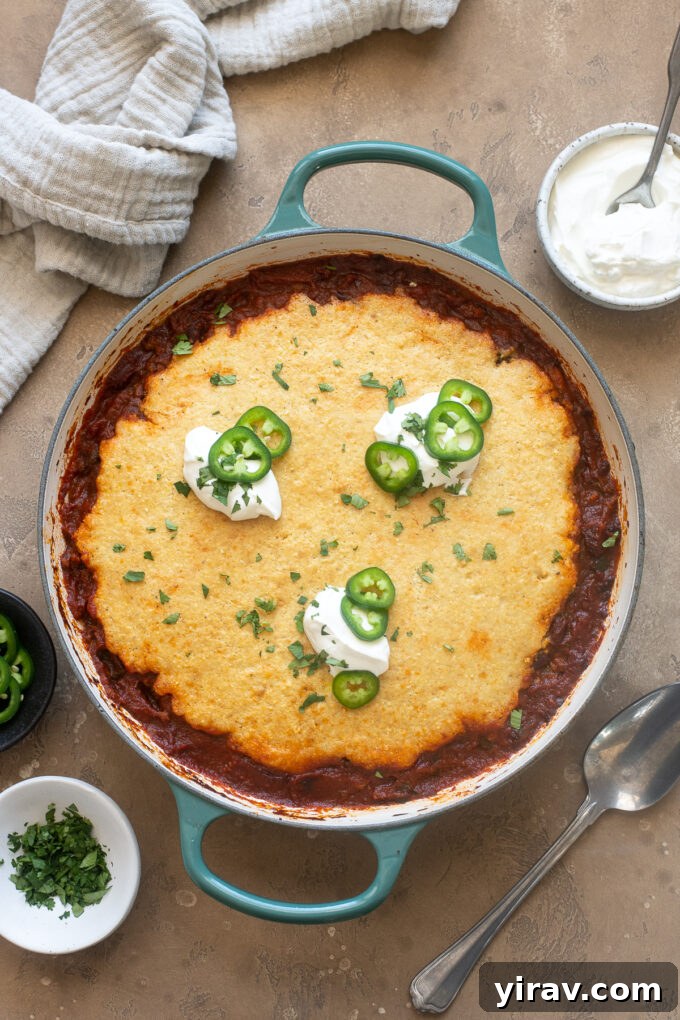 Comforting Chili Cornbread Bake 7 Chili cornbread casserole topped generously with sour cream and fresh jalapeño slices, ready to be enjoyed.