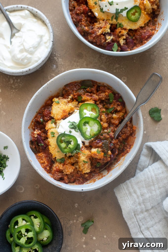 Comforting Chili Cornbread Bake 8 A serving of chili casserole with cornbread in a bowl, garnished with a dollop of sour cream and a sprig of fresh herbs.