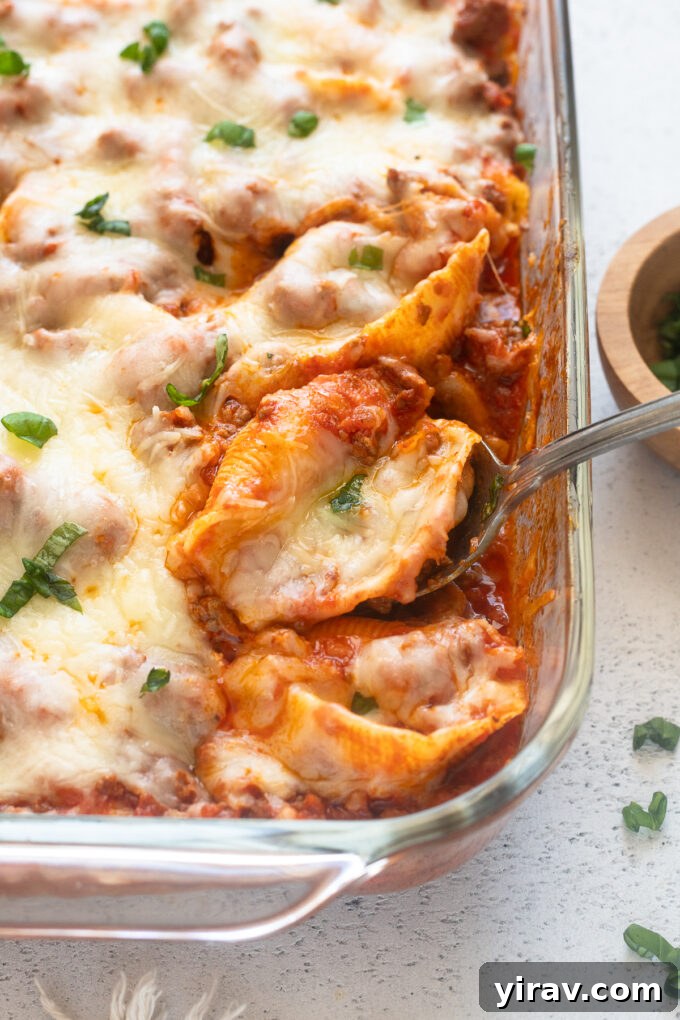 Serving spoon with cheesy, hearty stuffed shells with ground beef, ready to be enjoyed.