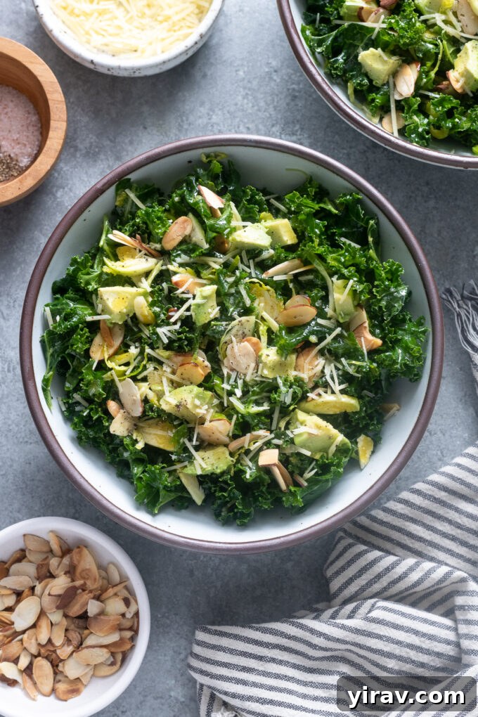 A vibrant kale salad featuring shaved brussels sprouts and creamy avocado in an elegant serving bowl.